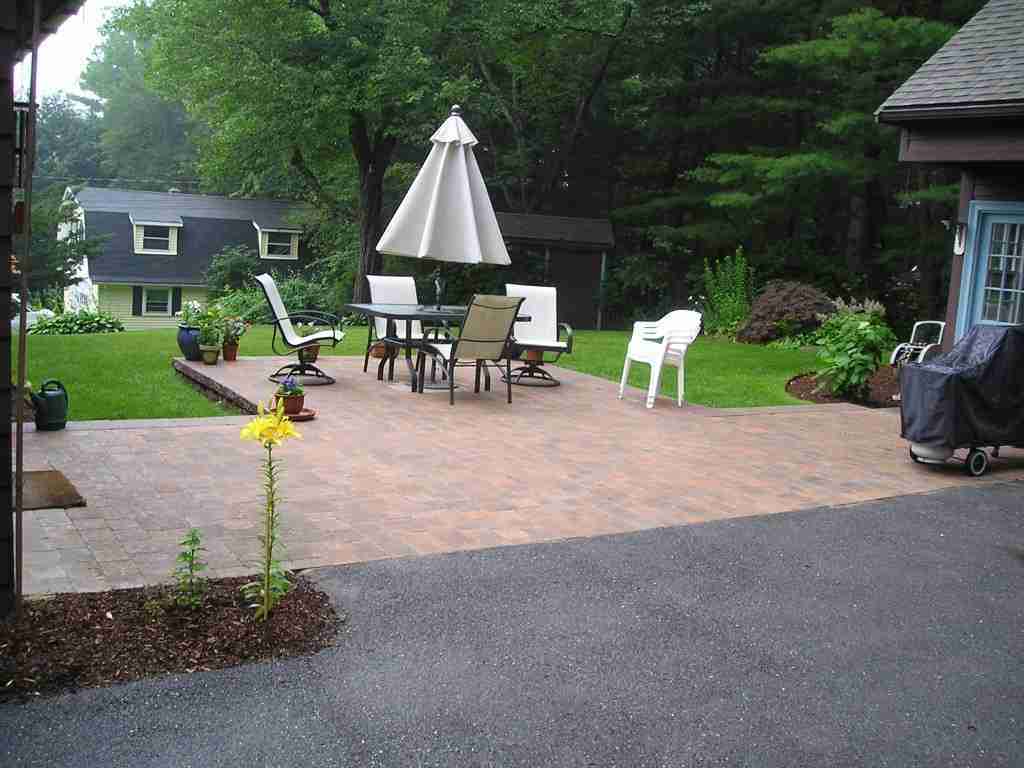 Patio and driveway with patio furniture and umbrella