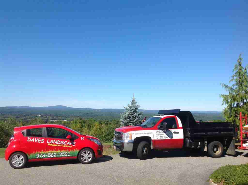 Closeup of two Dave's Landscape vehicles, a red minivan on the left and a red and white pickup truck on the right