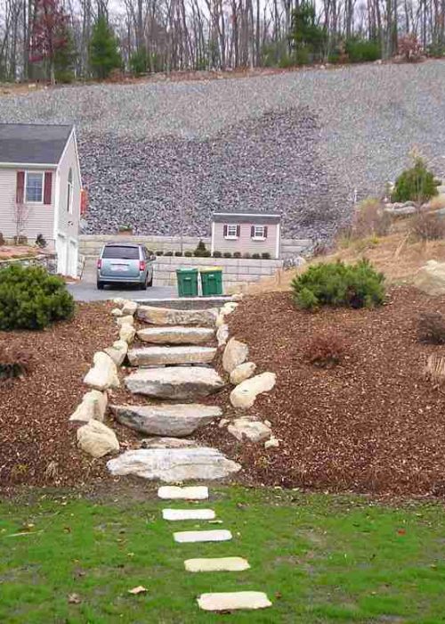 Walkway, lawn, and mulch with several bushes